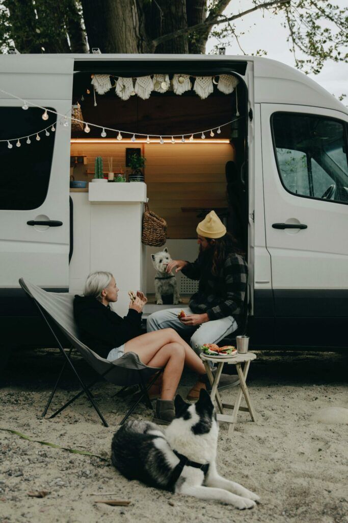 Paar entspannt vor dem Wohnmobil im Urlaub